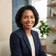 A smiling, diverse woman with healthy skin posing for a professional headshot in a modern, bright studio setting.