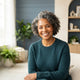 A diverse woman with a glowing complexion smiling warmly in a bright, modern, professional studio setting.